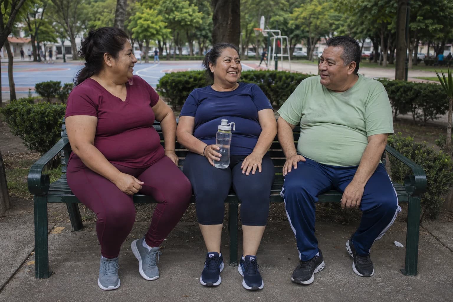 Tres adultos conversando en una banca de un parque después de caminar